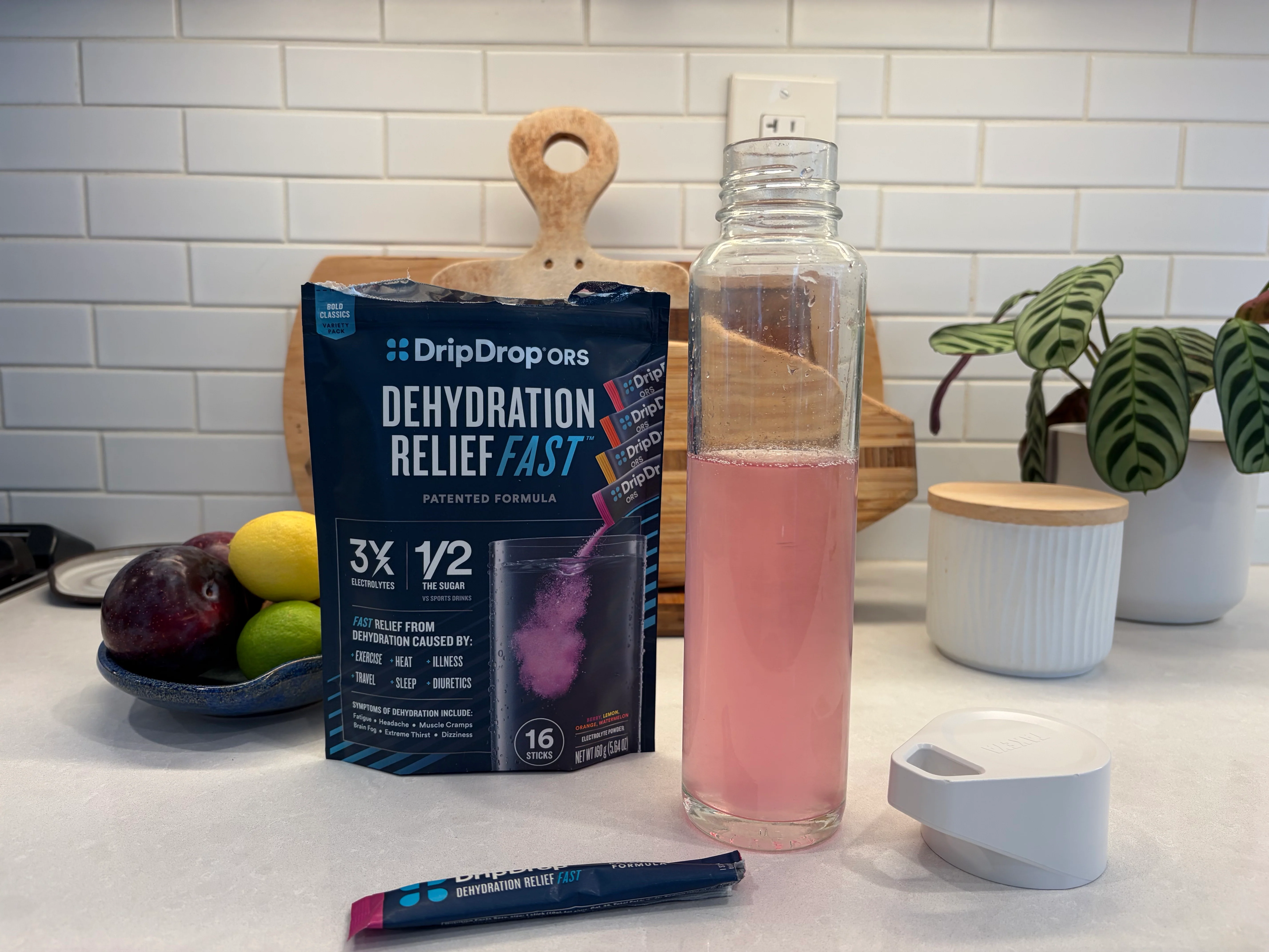 A bottle of oral rehydration solution sitting on a clean kitchen counter next to a baby medicine syringe and a small cup, natural window light, realistic photo