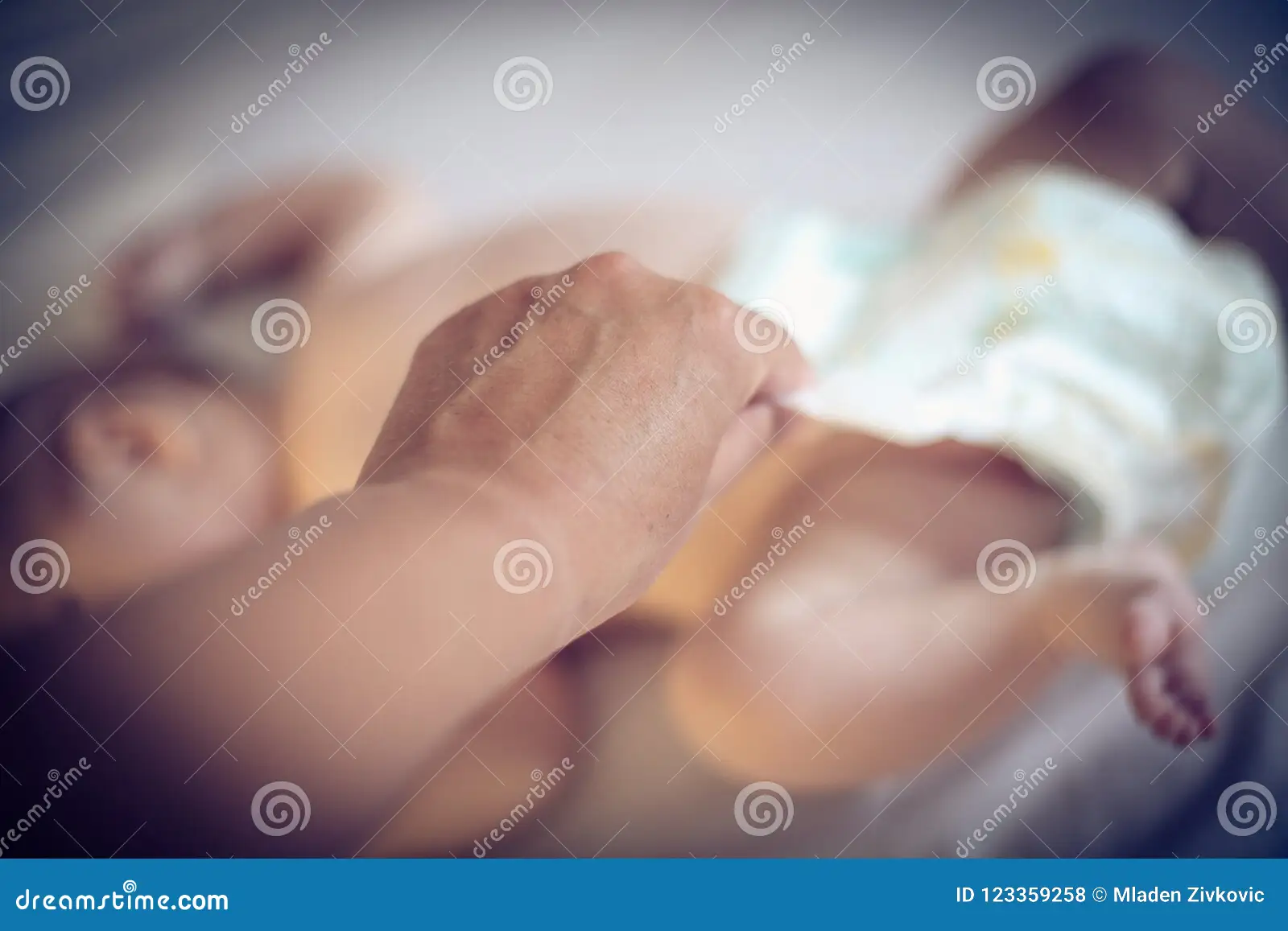A caregiver fastening a clean diaper on a newborn on a changing pad, with a small amount of soft yellow stool visible in the used diaper nearby, realistic home setting