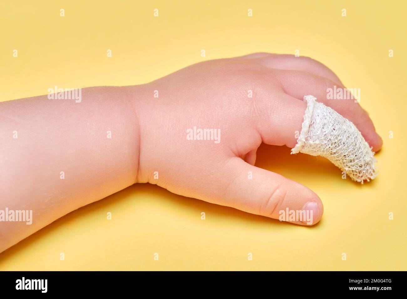 A close-up photo of a toddler’s small finger with a tiny adhesive bandage on the tip while the child holds a stuffed animal