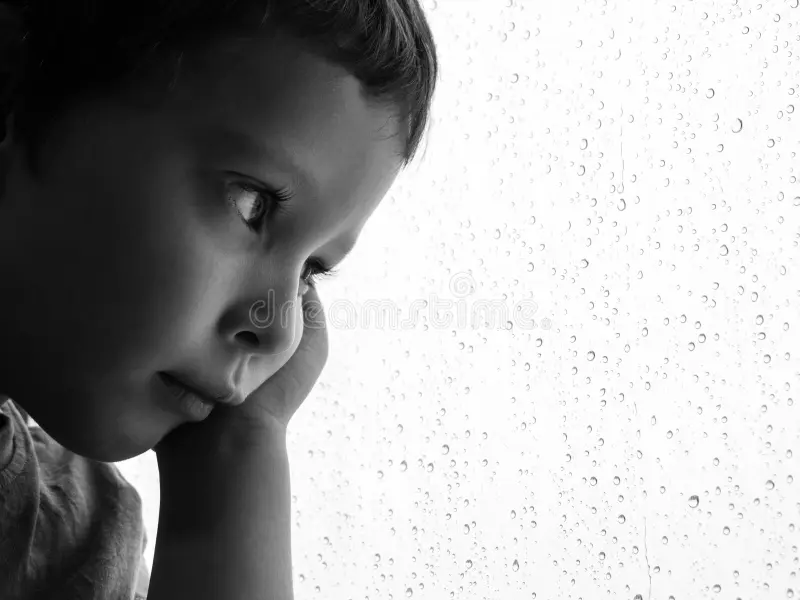 A close-up portrait photo of a toddler near a window with soft natural light reflecting in both eyes, realistic photography