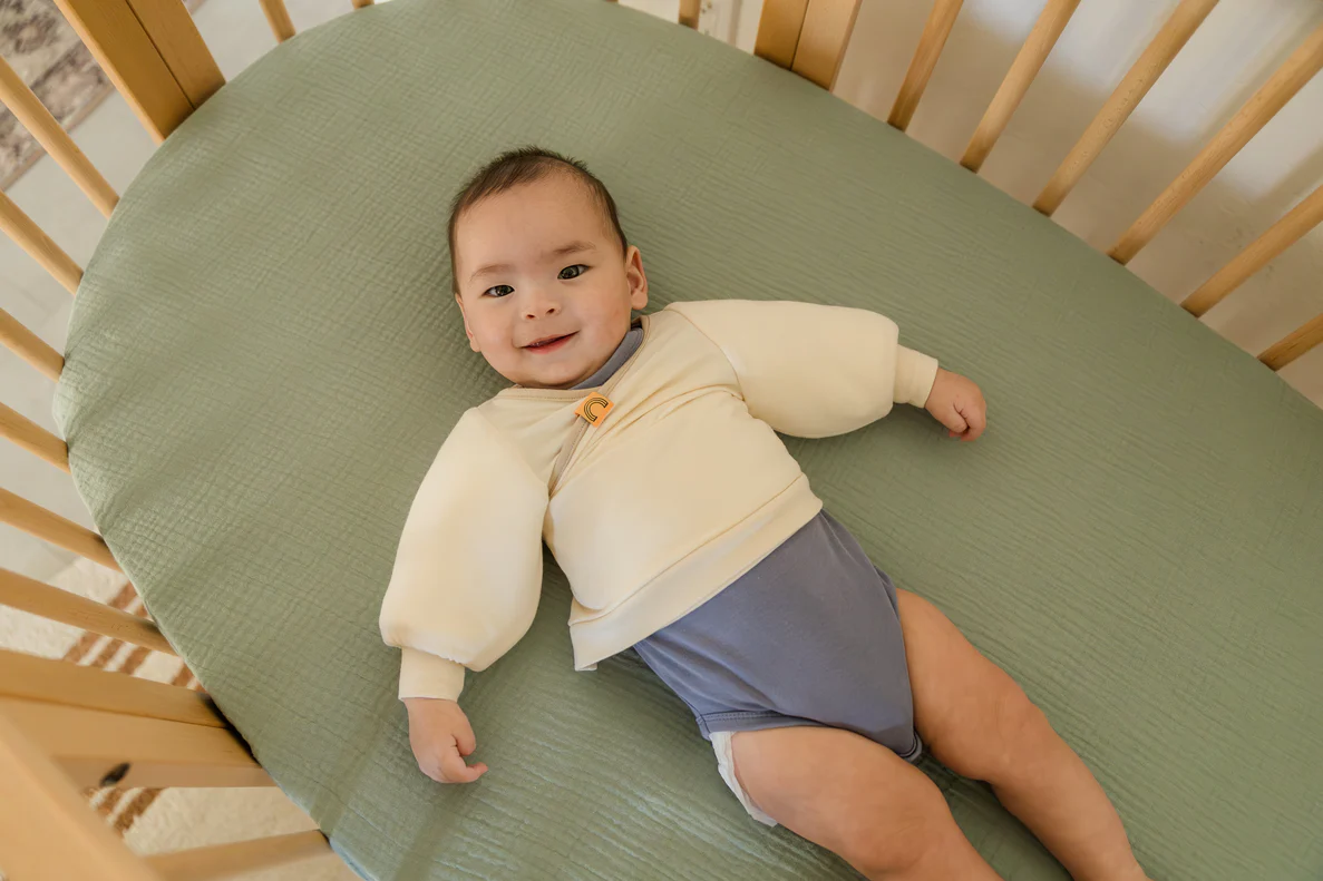 A five-month-old baby lying awake in a crib after a short nap, morning light coming through a window, candid real-life parenting photo