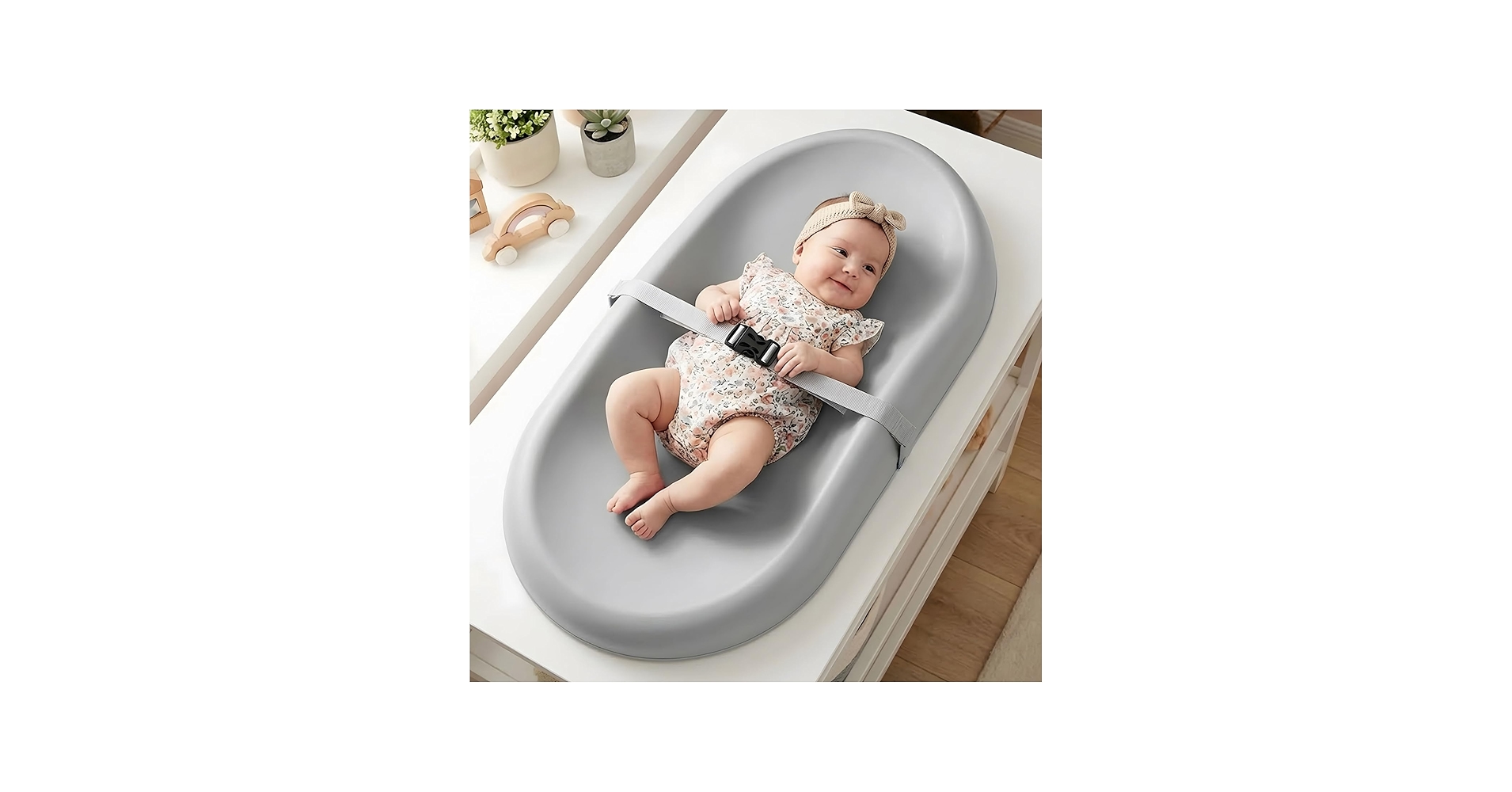 A newborn lying on a changing table with knees gently bent, face scrunched as if straining, while a caregiver's hands rest nearby in a calm, supportive moment, natural window light