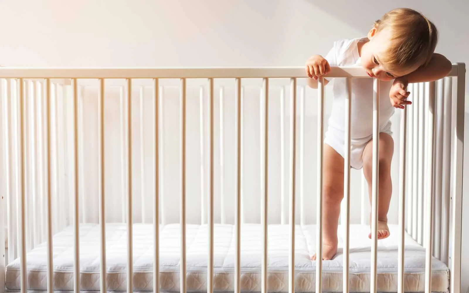 A nine-month-old baby sleeping on their back in a crib during the day with soft natural light coming through curtains, realistic photography style