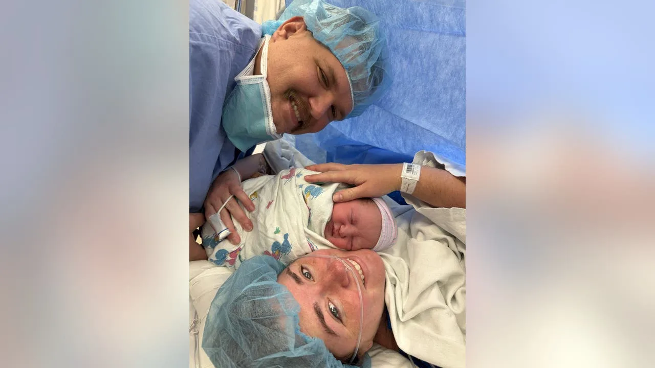 A nurse weighing a young infant on a clinic baby scale while a parent stands close by, medical office photo