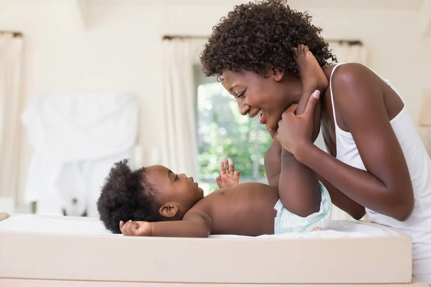 A parent changing a baby’s diaper on a changing table with wipes and a clean onesie nearby, realistic home setting