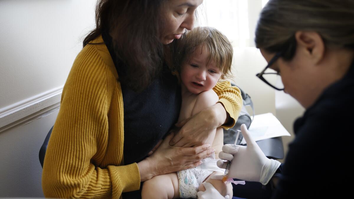 A parent cuddling a sleepy toddler on a couch at home after a vaccination appointment, cozy natural light photo