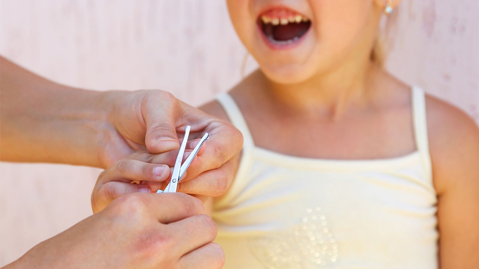 A parent gently trimming a toddler’s fingernails with small child-safe nail clippers at a kitchen table, soft natural light, realistic photograph