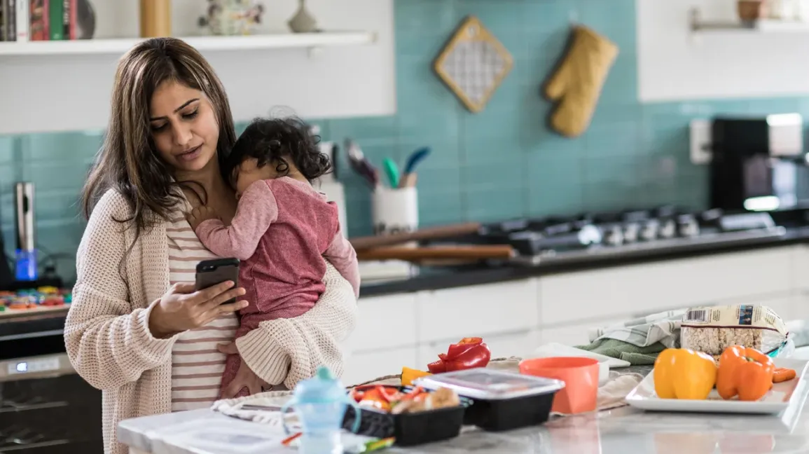 A parent hand expressing breast milk into a clean bottle on a kitchen counter, soft natural light