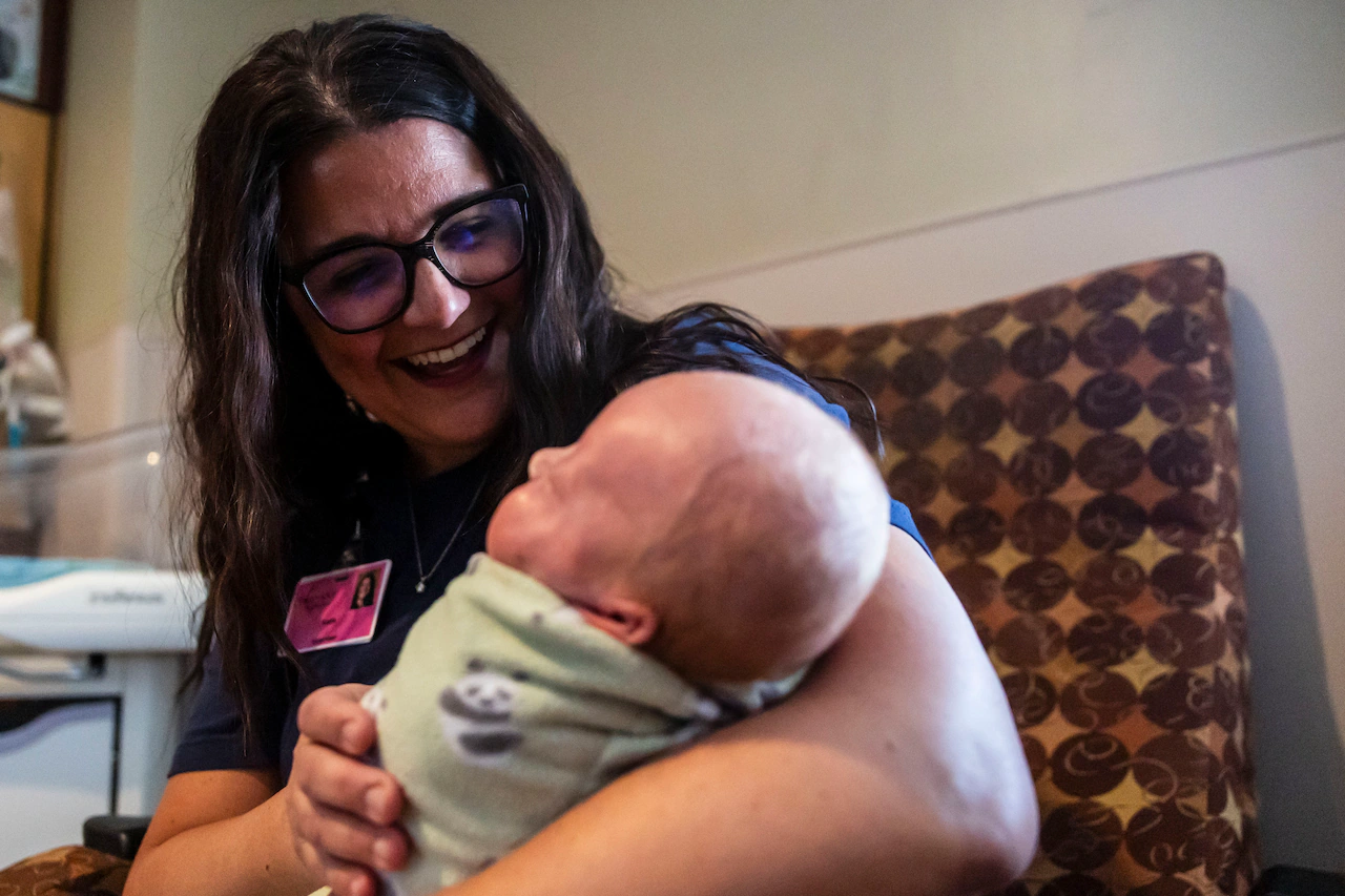 A parent holding a calm toddler in a pediatric clinic waiting room, natural light, candid photo