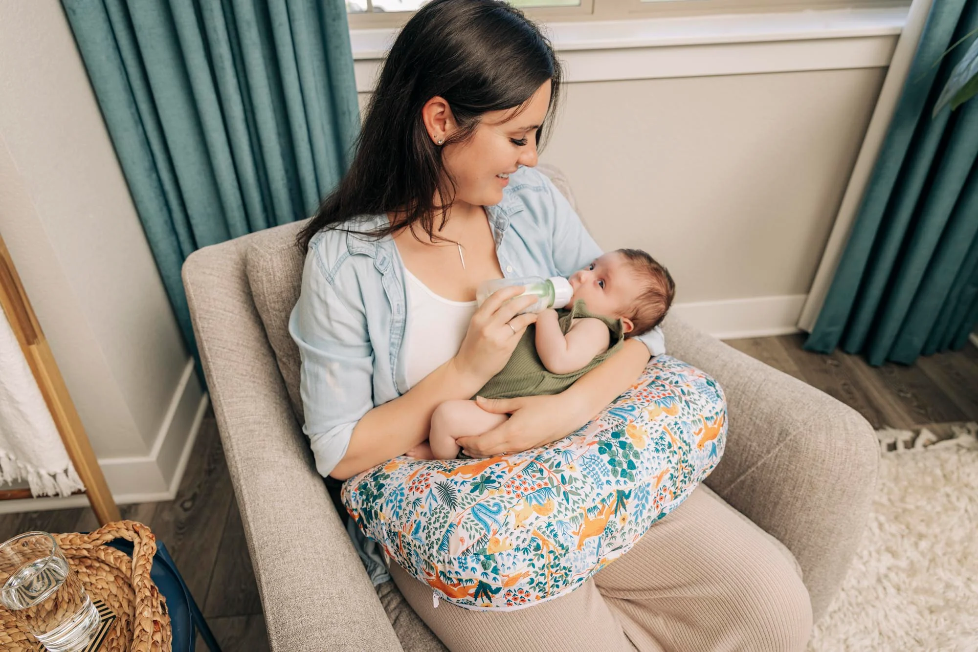 A parent holding a newborn in a semi-upright position while bottle feeding slowly with the bottle held more horizontal, warm natural window light, real-life home photo