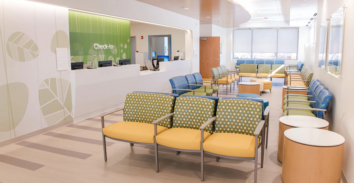 A parent holding a sleepy toddler in a bright urgent care waiting room, realistic documentary-style photo