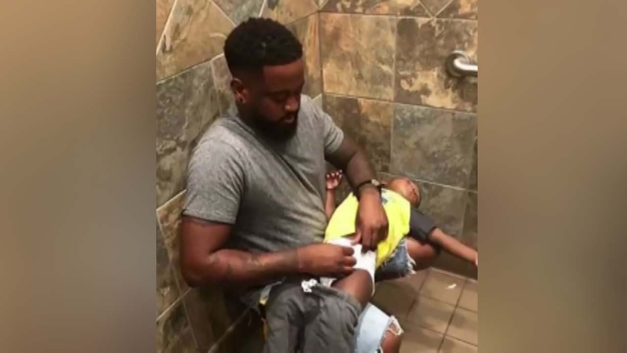 A parent holding a smartphone above a diaper on a bathroom counter to take a clear photo for a pediatrician, realistic photo