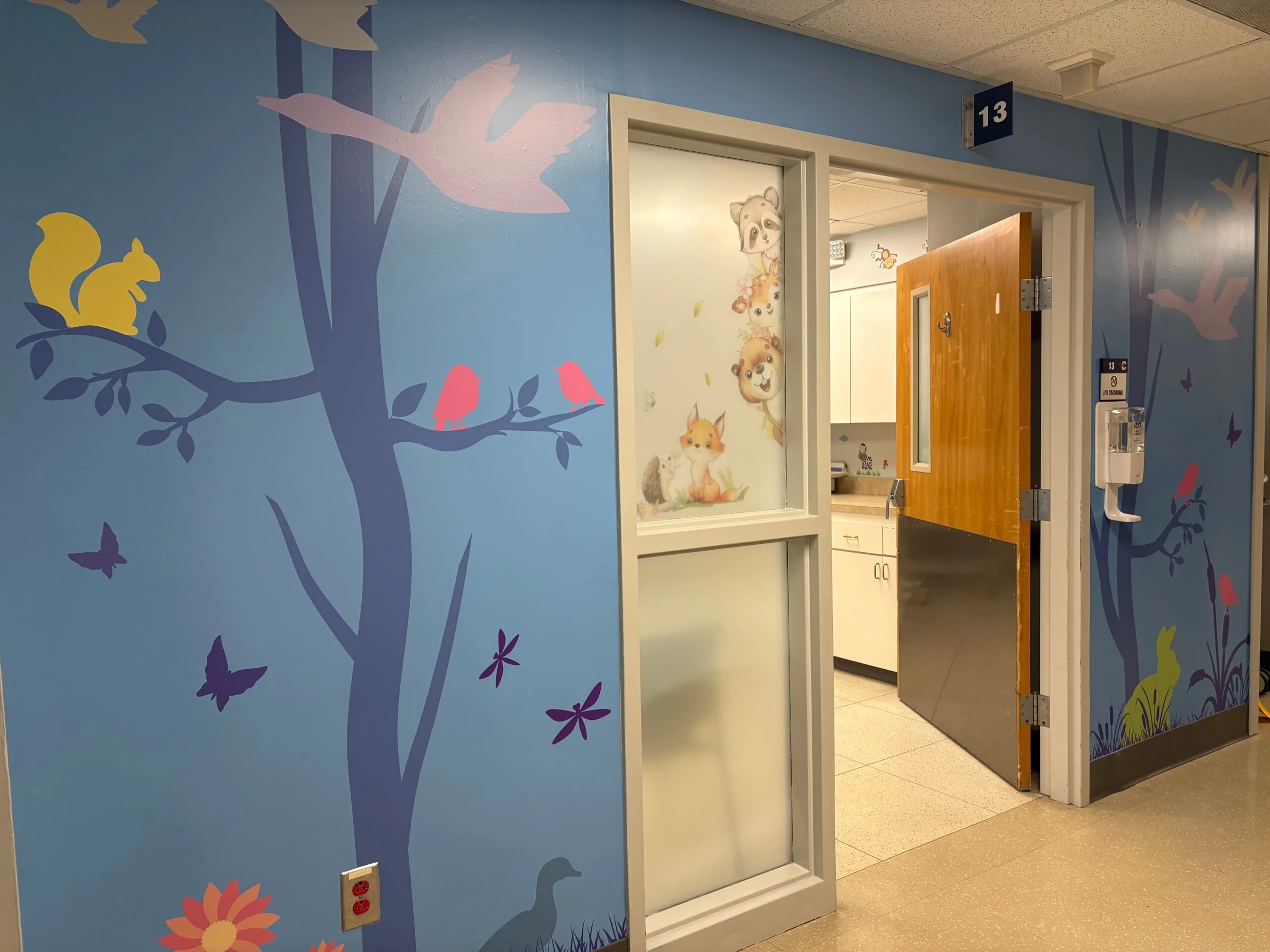 A parent holding a toddler in a calm pediatric clinic waiting room with neutral decor, candid healthcare photo