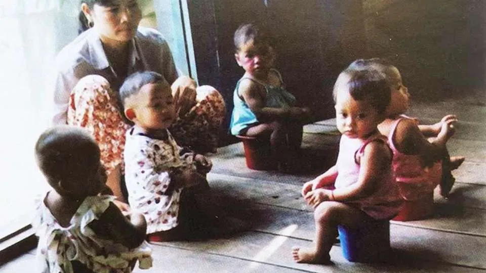 A parent kneeling beside a toddler in a bathroom, checking a diaper with a worried expression, realistic indoor lighting, real-life photo