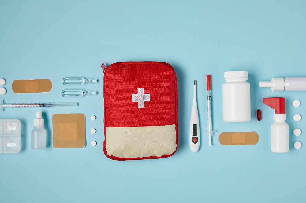 A parent organizing a small home first aid kit with bandages and common medicine bottles