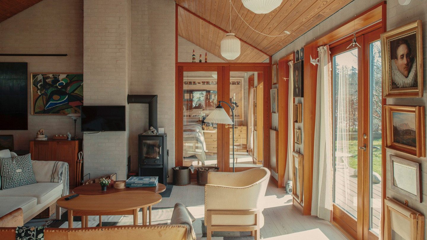 A parent sitting on the floor with a preschool child playing with wooden letter blocks in a sunlit living room, real-life candid photo