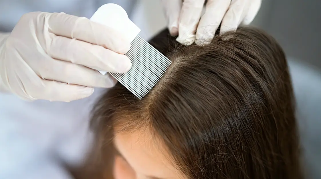 A pediatric dermatologist gently parting a young child’s hair to examine the scalp under bright clinic lighting, real photographic style