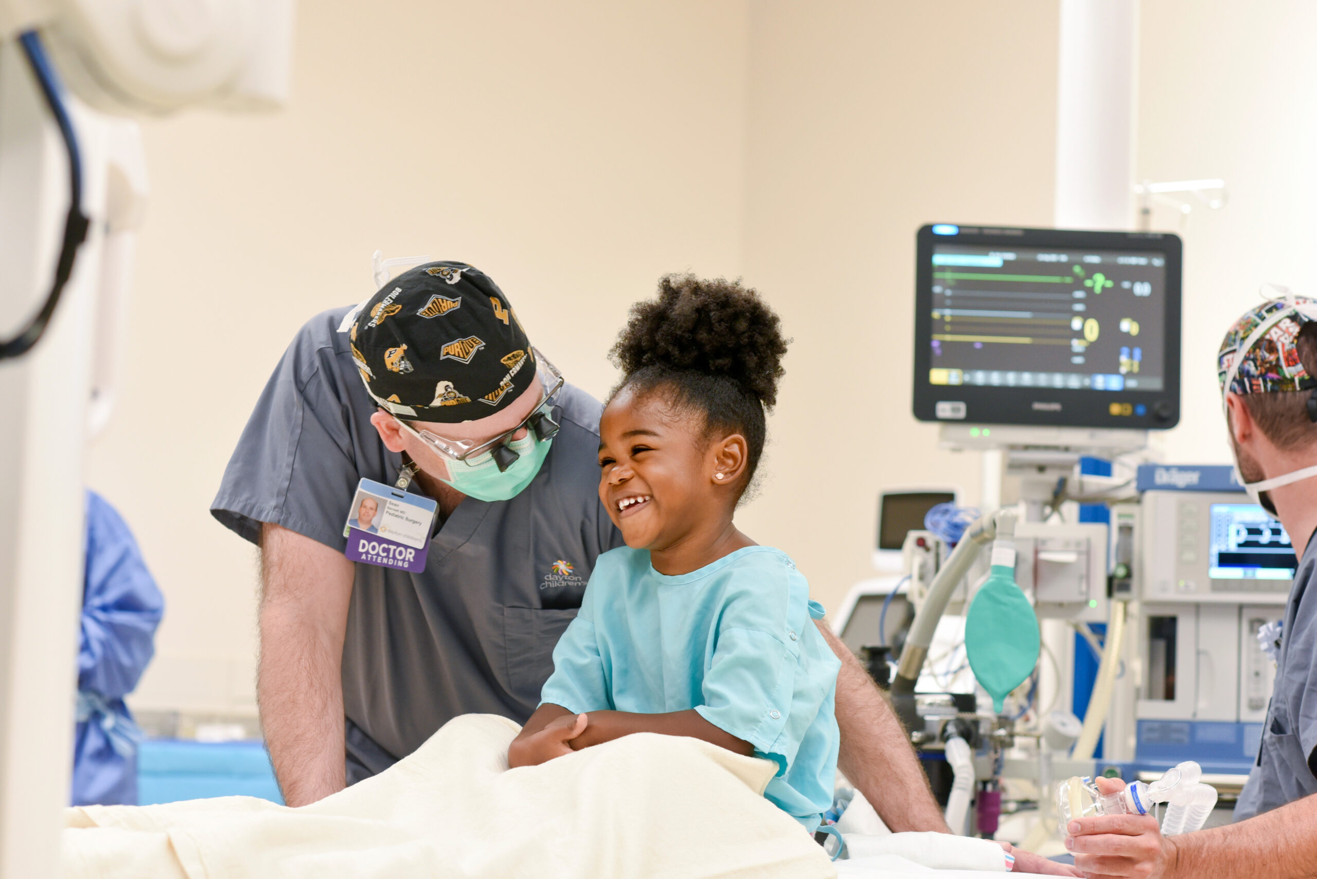 A pediatric surgeon speaking with parents holding a baby during a consultation in a clinic exam room, candid medical photo