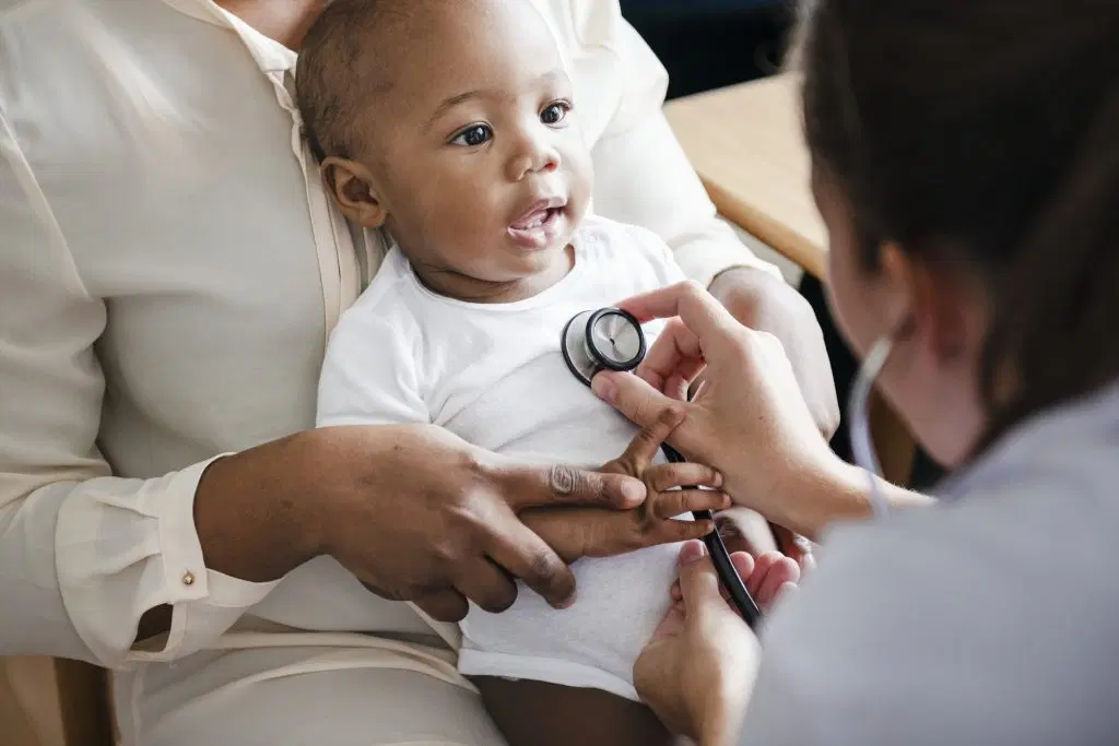 A pediatrician sitting with a parent in an exam room reviewing a child’s lab results on a tablet during a well child visit, documentary photo