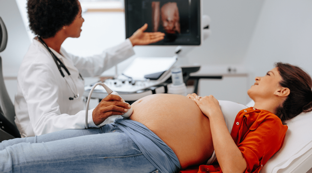 A pregnant person lying on an exam table during a prenatal ultrasound while a clinician holds the ultrasound probe, realistic clinical photography