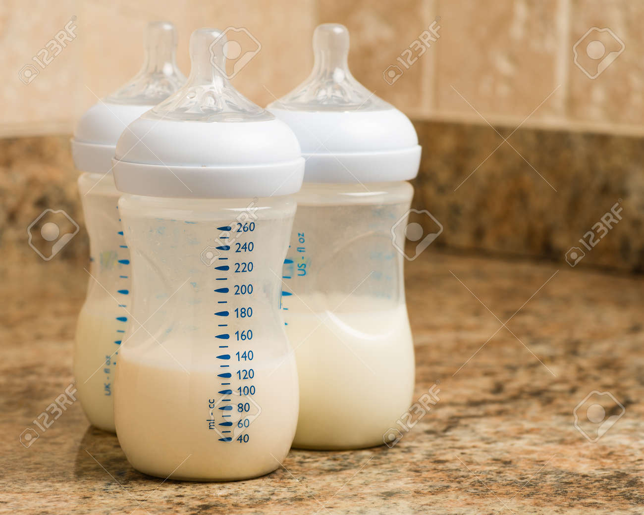 A prepared infant formula bottle sitting on a clean kitchen counter next to a measuring pitcher, natural daylight, real photo
