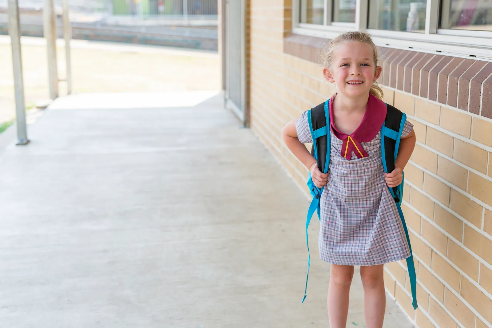 A preschool-age child standing with a parent at daycare pickup, mid-blink with slightly scrunched eyes, candid real-life photo