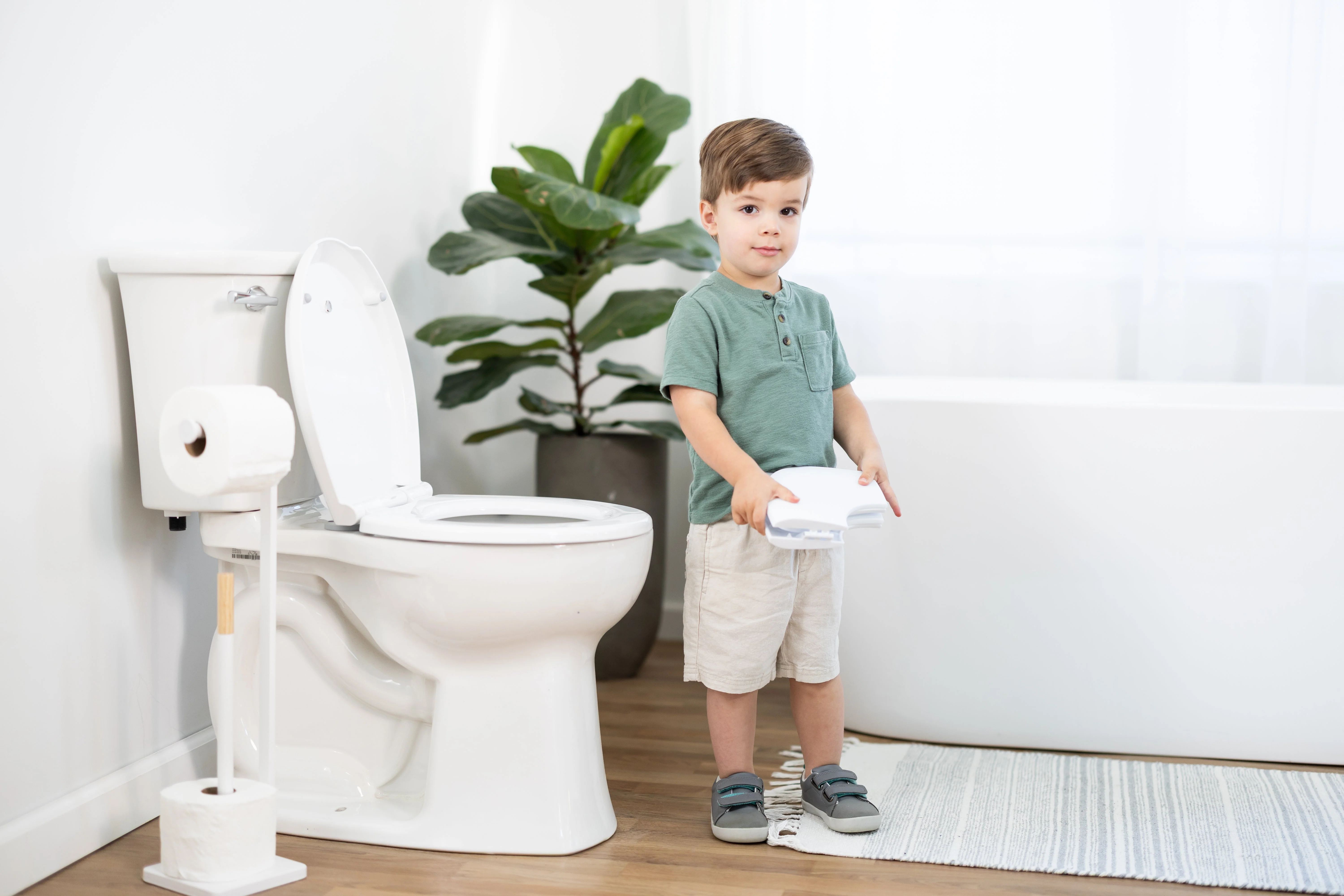 A preschool-aged child in pajamas standing in a bathroom doorway looking upset while a parent kneels nearby offering comfort, real-life candid photo