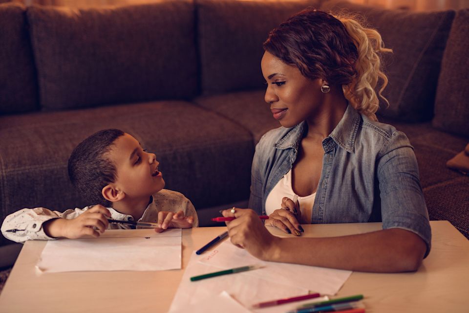A preschool-aged child sitting on a couch and talking to a parent in a bright living room, candid family photograph