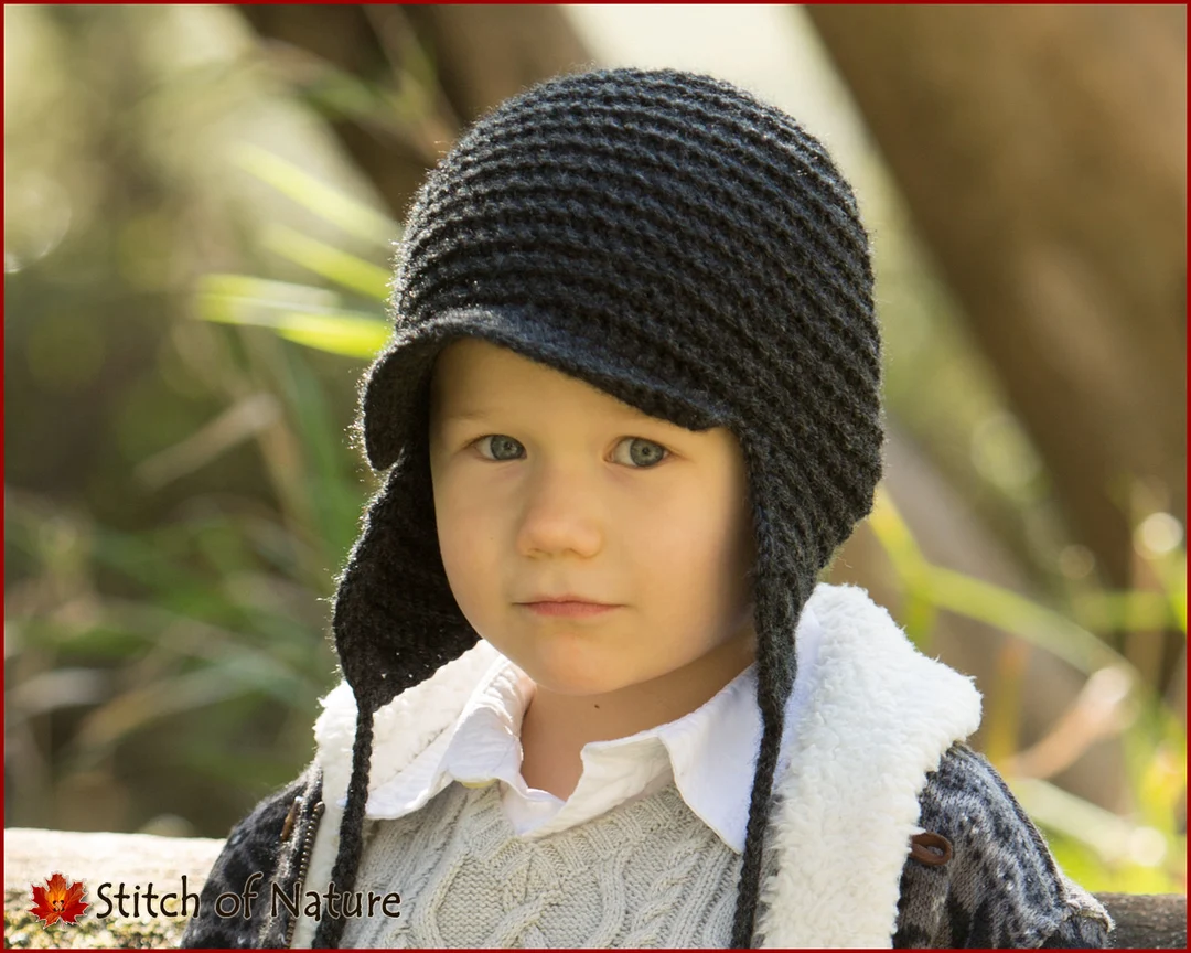A real photograph of a toddler wearing a winter hat that fully covers the ears while standing outside on a cold day