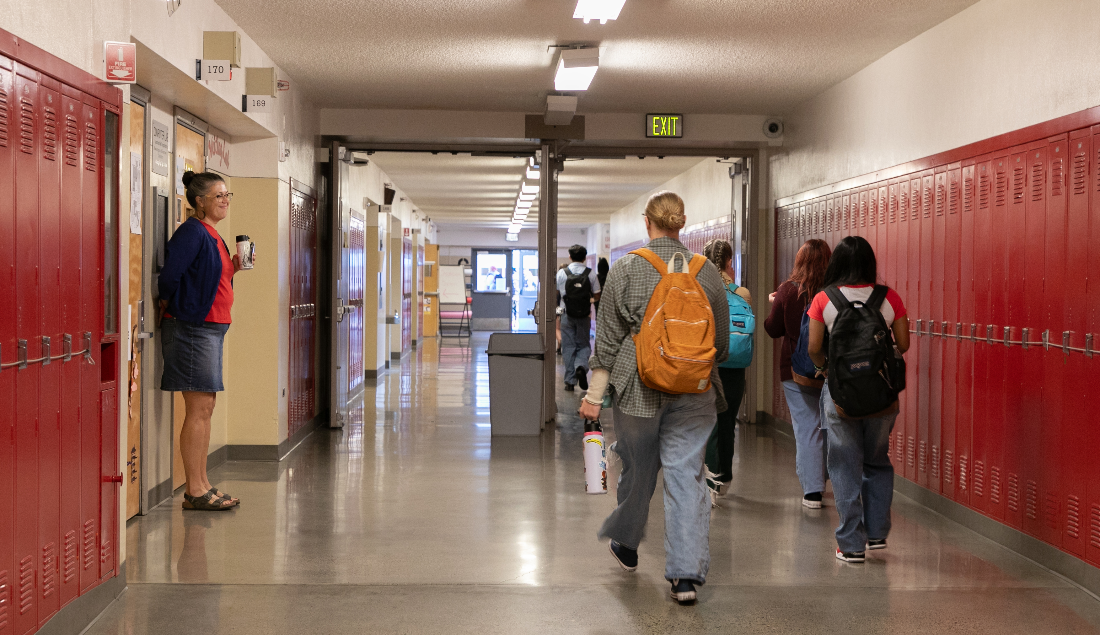 A school-age child walking down a school hallway with a backpack while favoring one leg