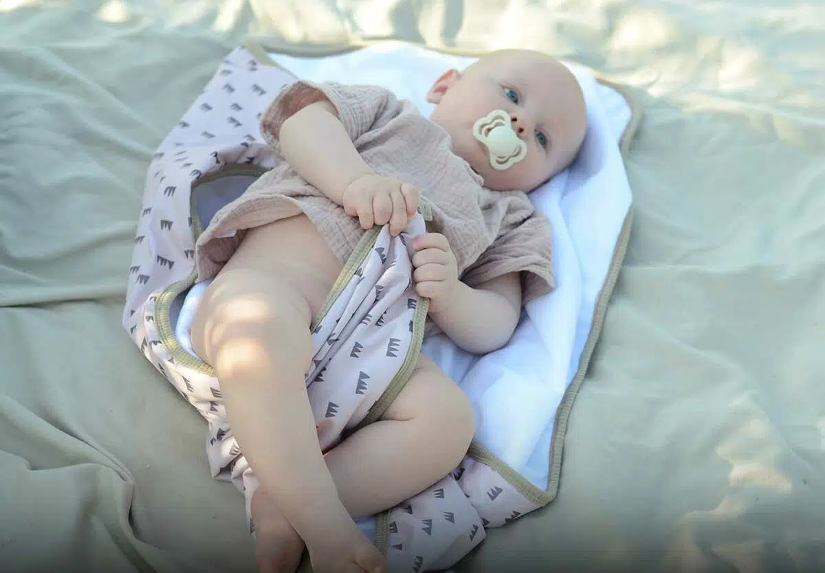 A tired parent changing a toddler's diaper on a changing table at home in soft morning light, realistic photo