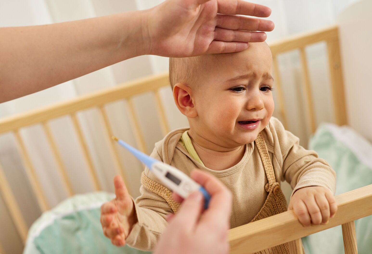 A tired parent gently checking a baby's temperature with a digital thermometer in a softly lit nursery at night, realistic photography style