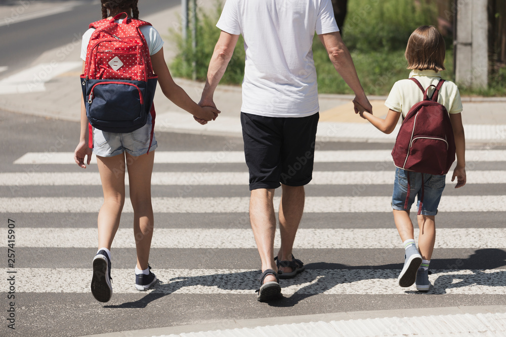 A toddler holding a parent’s hand while walking across a parking lot crosswalk toward a store entrance in daylight, real-life candid photo style