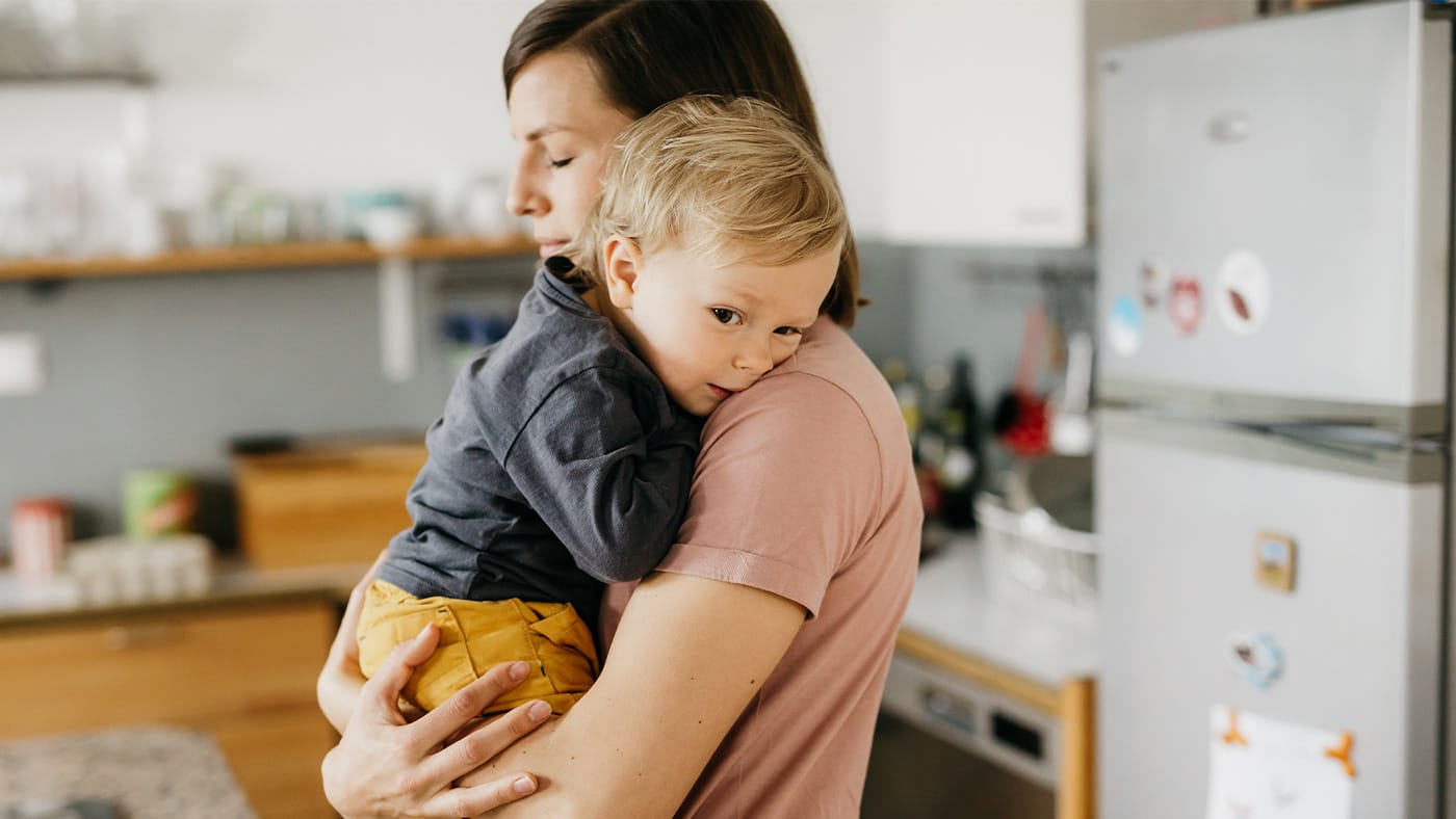 A toddler in pajamas holding their stomach while standing near a bathroom doorway, candid home photo