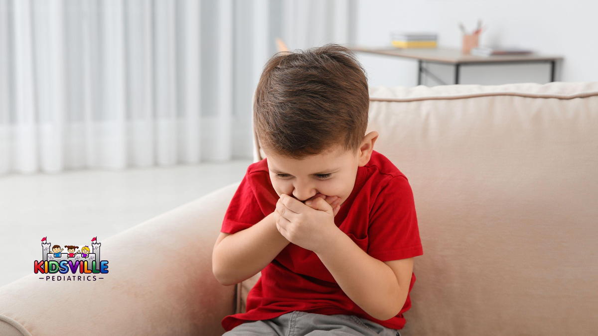 A toddler sitting on a living room couch holding their belly with a worried expression, an empty ice cream bowl on the coffee table in the background, candid home photo