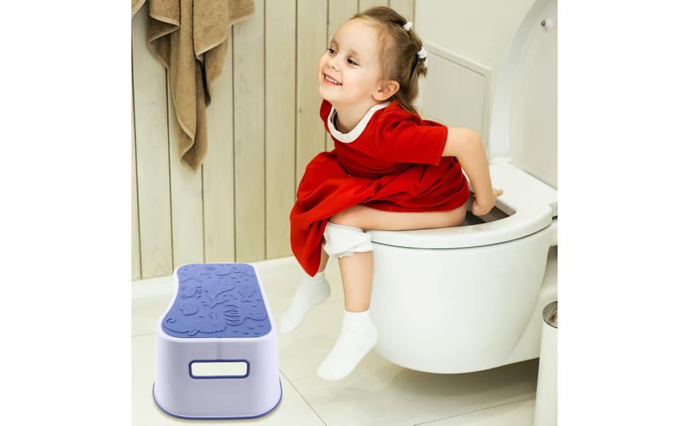 A toilet-trained child sitting comfortably on a toilet with feet supported on a small footstool in a bright bathroom, real-life photo
