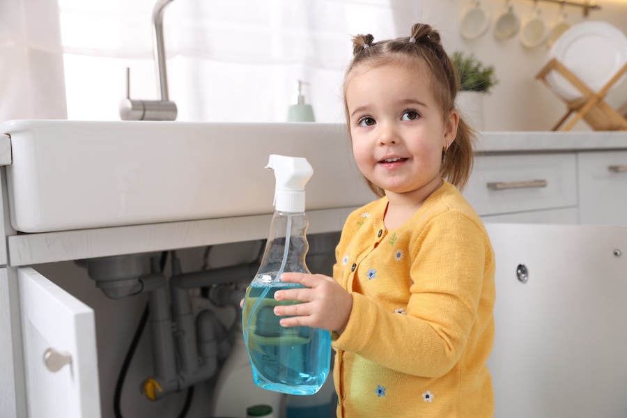 A worried parent holding an open child-resistant medicine bottle while speaking on a phone in a softly lit kitchen, realistic documentary-style photo