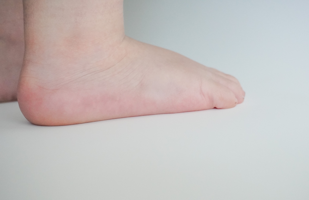 An elementary school-age child sitting on a bed in soft lamplight, rubbing their calves with a frustrated, tired expression while a parent sits nearby, real-life bedtime scene